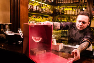 A man presents an elaborately housed cocktail
