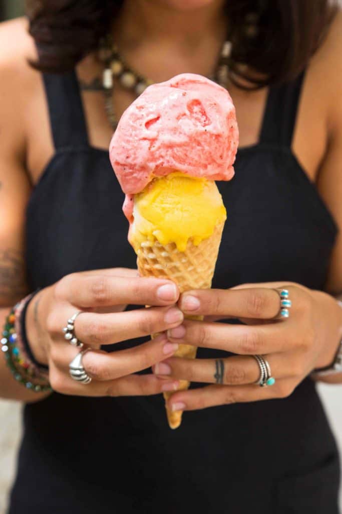A woman holds a fruity ice cream cone