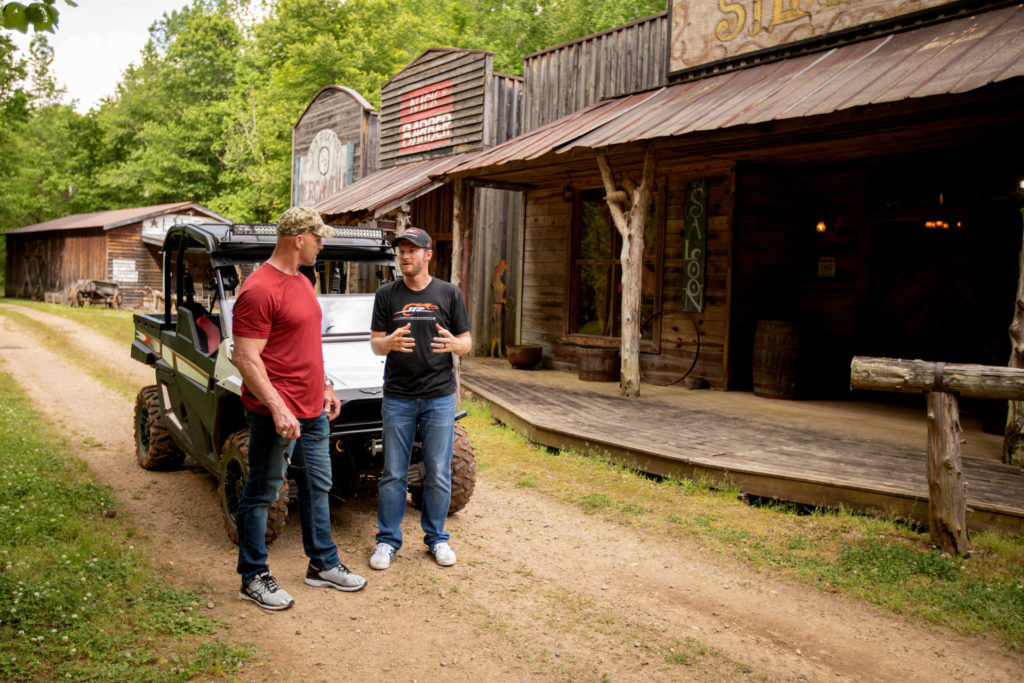 Earnhardt Jr. and Steve Austin talking in front of a jeep.