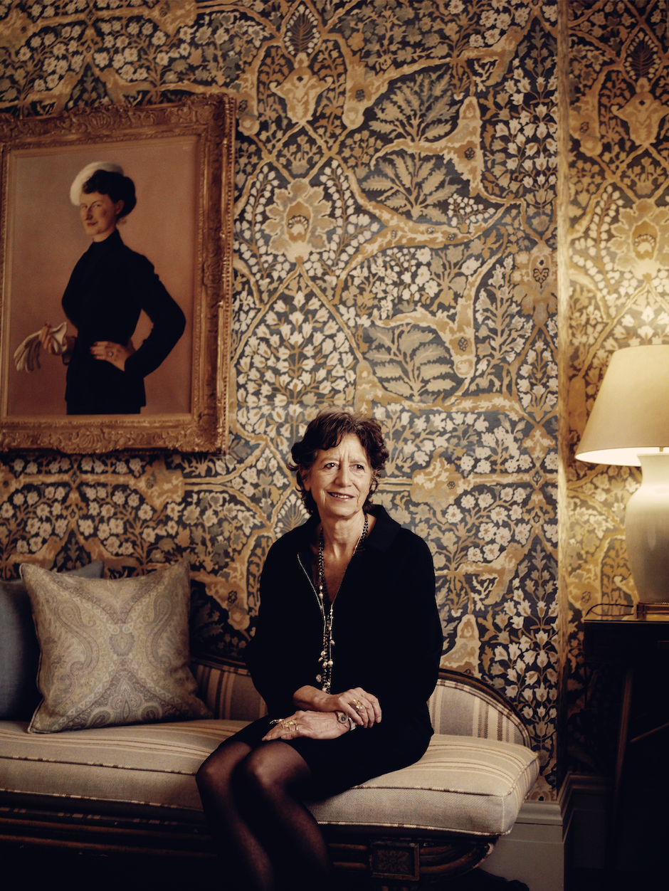 Olga Polizzi sitting on a decorative sofa in a stylish hotel room.