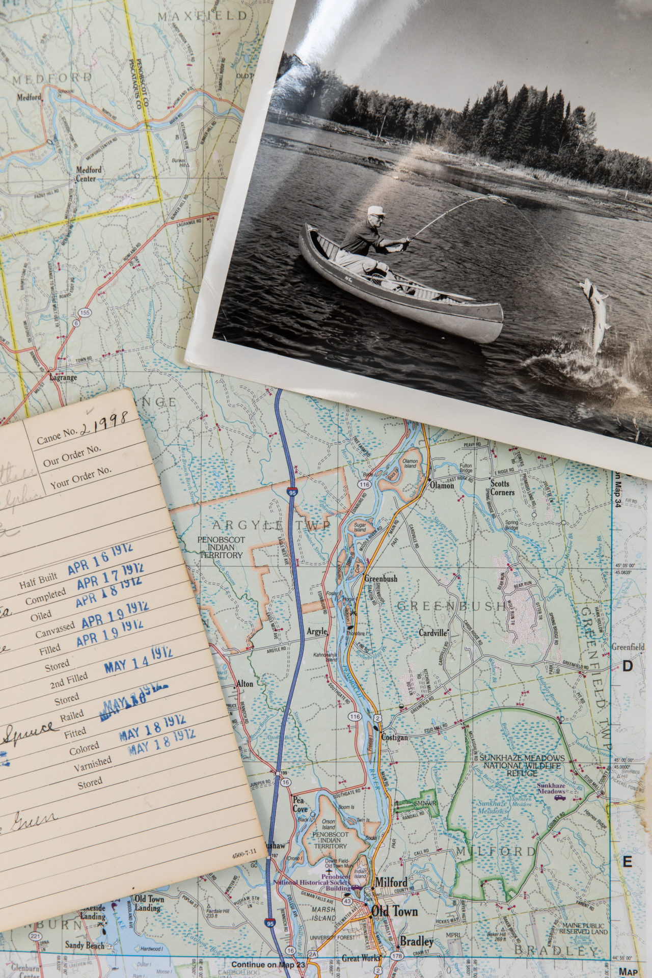 A map, notebook and black and white photograph of a man fishing.