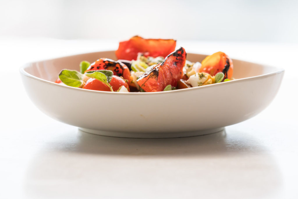 Tomato salad in a white bowl.