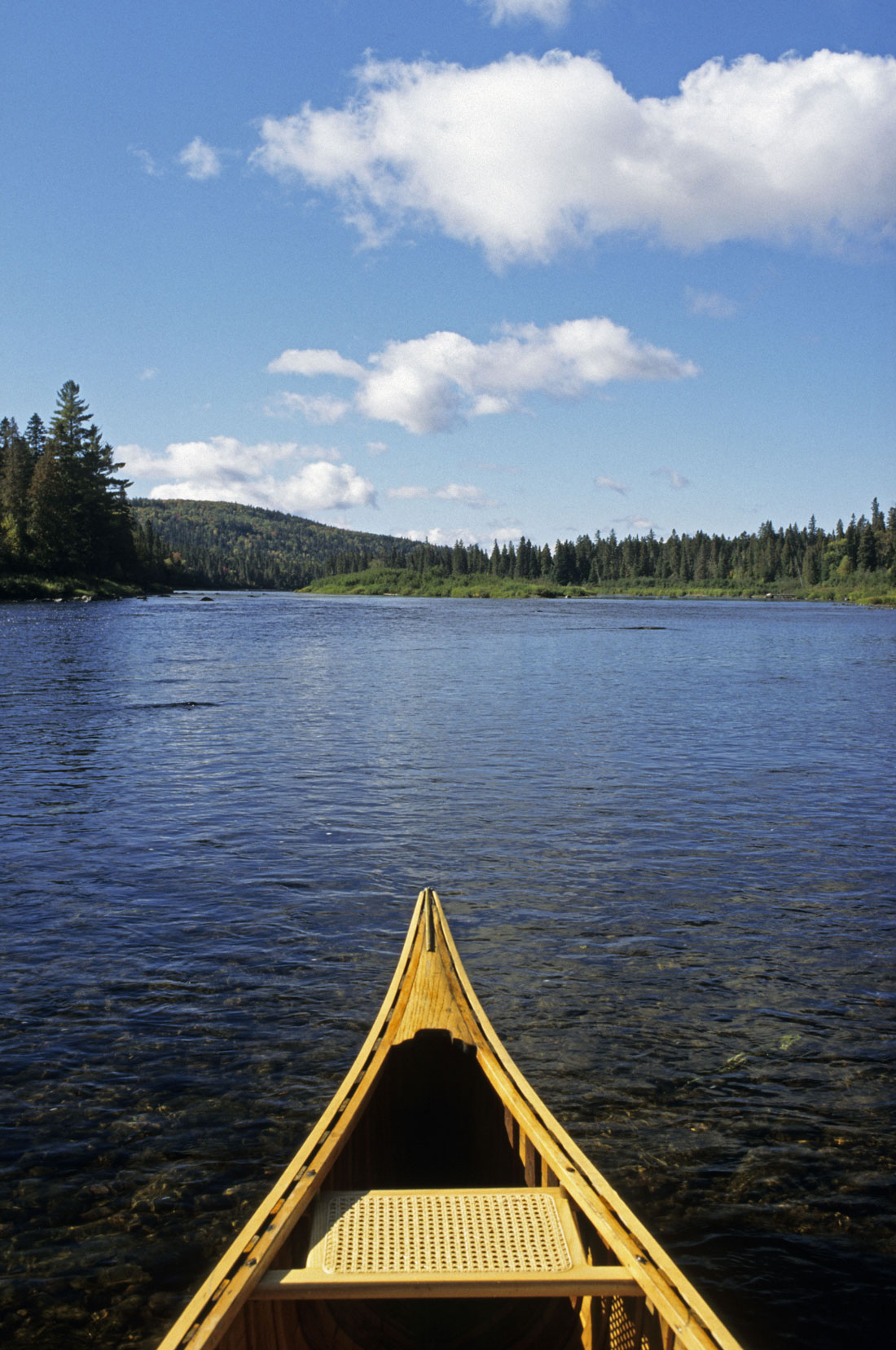 The tip of a canoe on a stretch of water. 