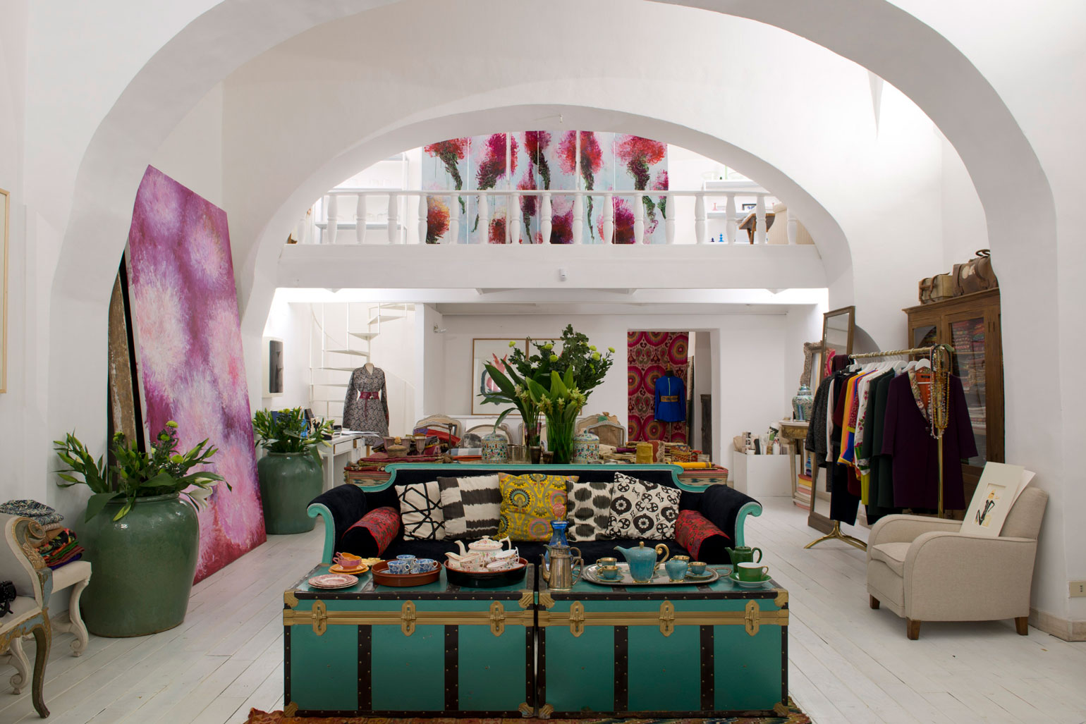 A white shop space filled with art, clothing and furniture. 