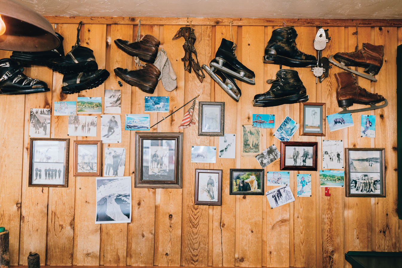 A timber wall with ice skates and pictures hanging on it.