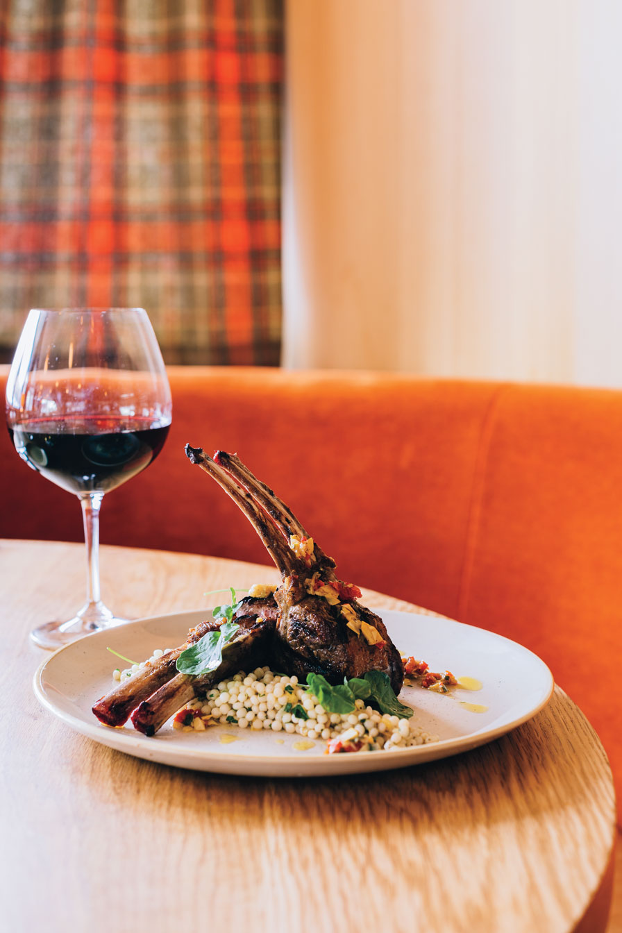 Lamb chops on a plate with a glass of red wine.