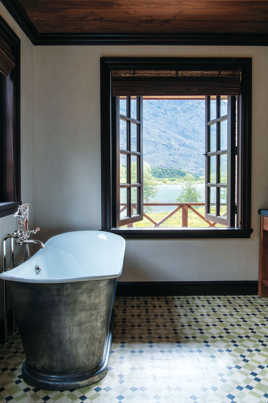 A bathtub in a bathroom with a view out to lush scenery. 