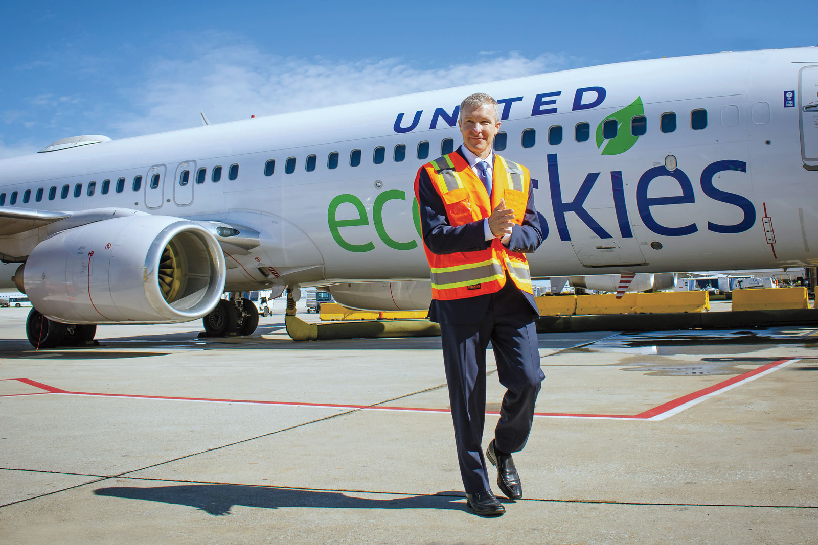 A man in high-vis clothing walks beside a plane.