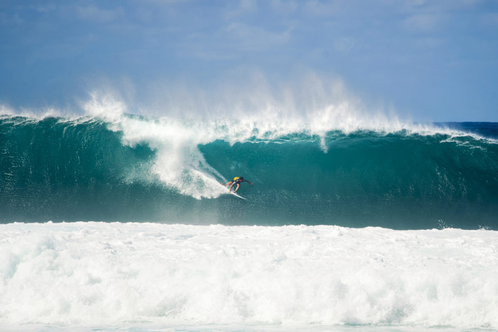 A surfer standing a huge wave.