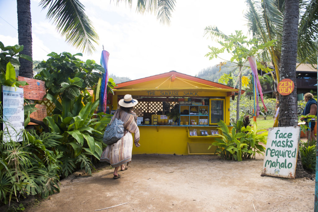 A sA colourful hut selling food, a woman standing in front of it.