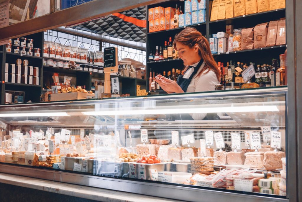 A woman standing behind a large deli counter