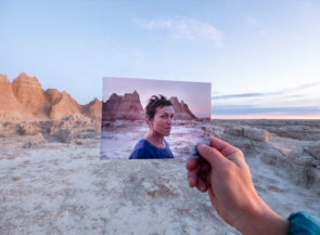 A person holding a picture in front of a desert.