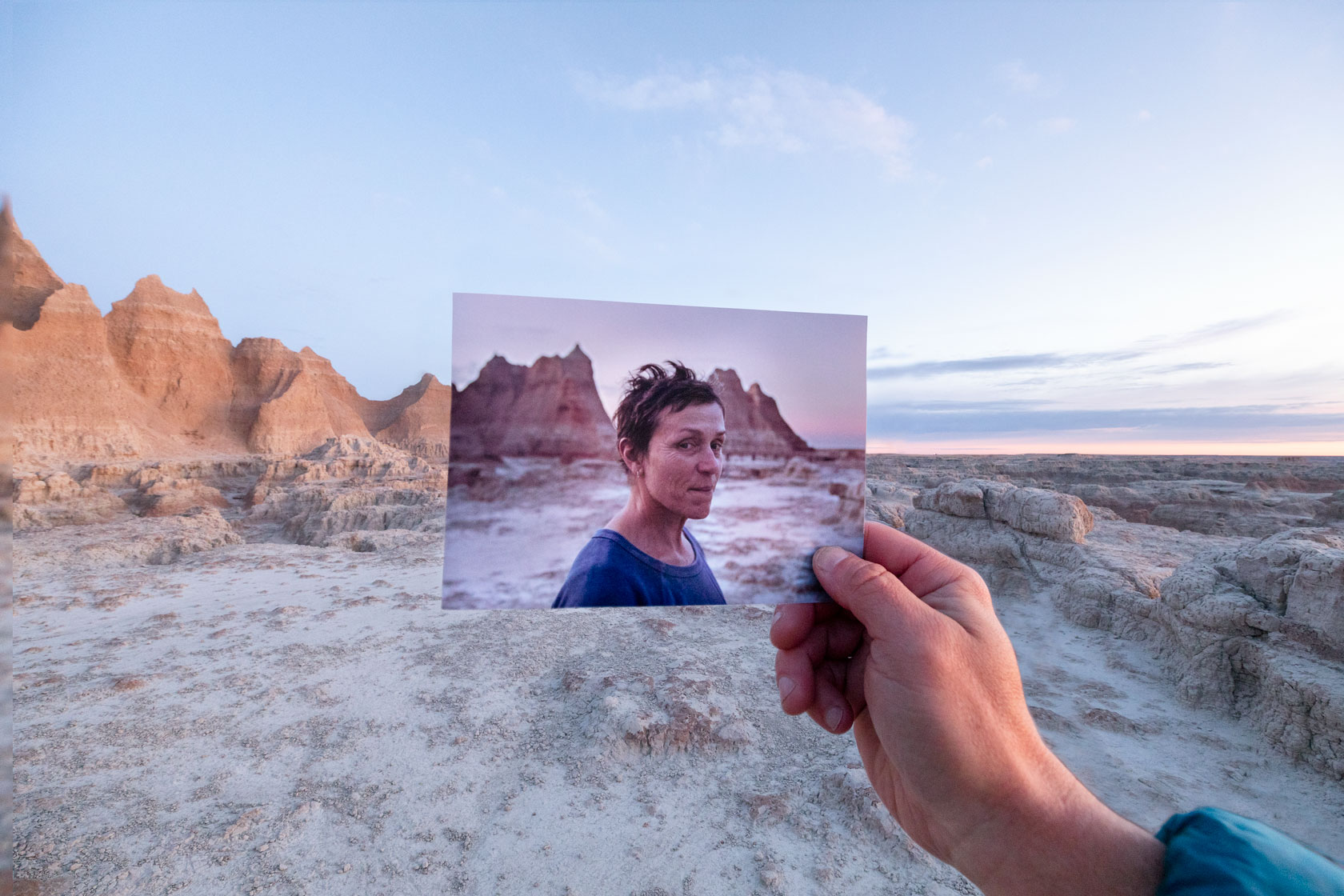 A person holding a picture in front of a desert.
