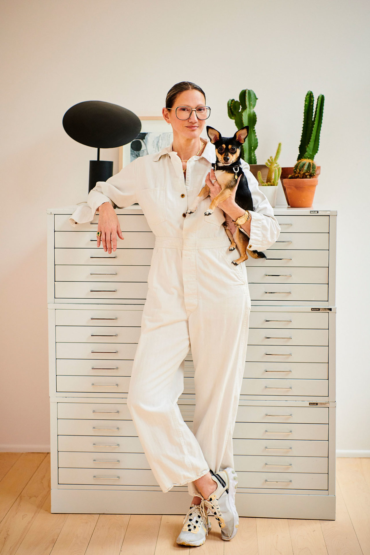 A woman in a white working suit holding a small dog.