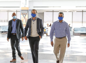 Three men walking, wearing masks.