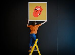 A person putting a Rolling Stones picture on the wall