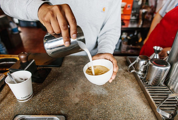 A barista pours milk into a coffee